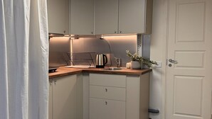 Eine Küche mit weißen Schränken, einer Holz Arbeitsplatte, einem Wasserkocher und einem Spülbecken.