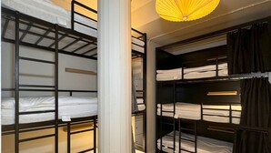 Ein Zimmer mit Etagenbetten, einer zentralen Säule und einer Hängeleuchte.