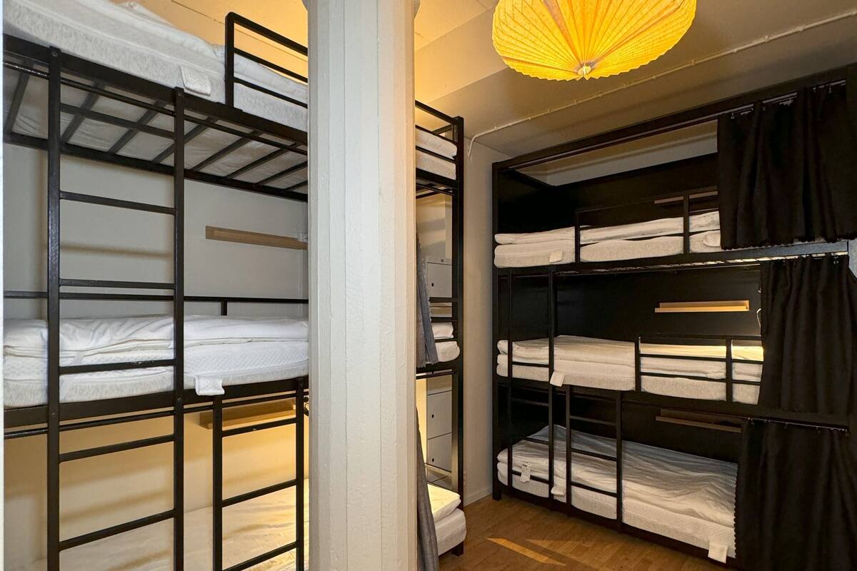 Une pièce avec des lits superposés, un pilier central et un luminaire suspendu.