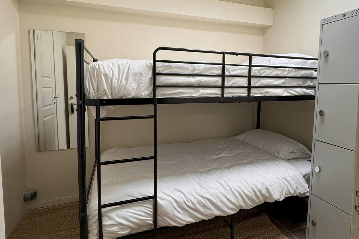 Une chambre avec un lit superposé, une lucarne, une porte et un petit placard.