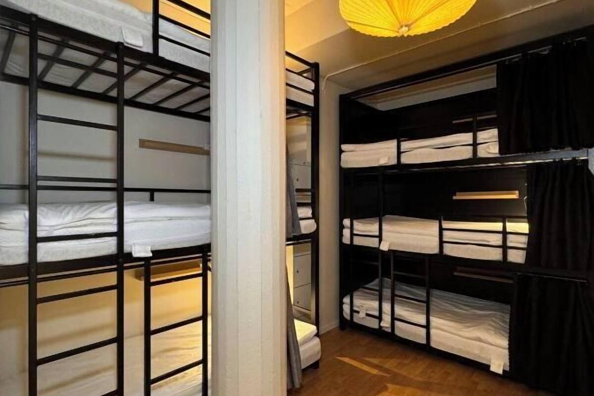 Des lits superposés dotés de compartiments de rangement, un plancher en bois et un luminaire suspendu.