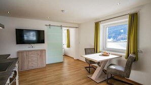 A modern kitchen with a built-in stove, a wooden cabinet, and a flat-screen TV mounted on the wall. - Vacation apartment Cafe Max Top 2 (Trins)