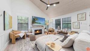 A spacious living room with a fireplace, comfortable seating, and large windows offering views of the outdoors. - Beach Treehouse Natures Hideaway Close to 30A (Santa Rosa Beach)