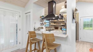 A modern kitchen with two wooden chairs, a central island, and a black range hood. - Beach Treehouse Natures Hideaway Close to 30A (Santa Rosa Beach)