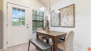 A dining area with a wooden table, chairs, a bench, and two wall-mounted light fixtures. - Beach Treehouse Natures Hideaway Close to 30A (Santa Rosa Beach)