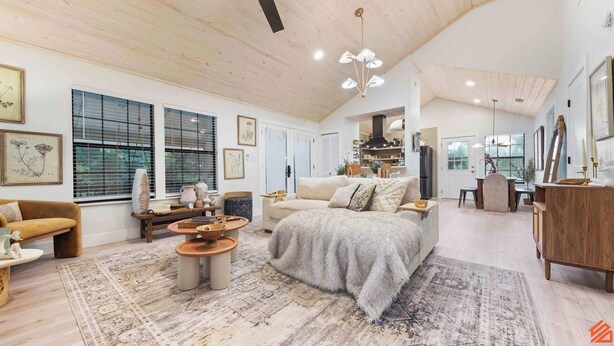 A spacious living area with a large sofa, a coffee table, and a dining area with a wooden table and chairs. - Beach Treehouse Natures Hideaway Close to 30A (Santa Rosa Beach)