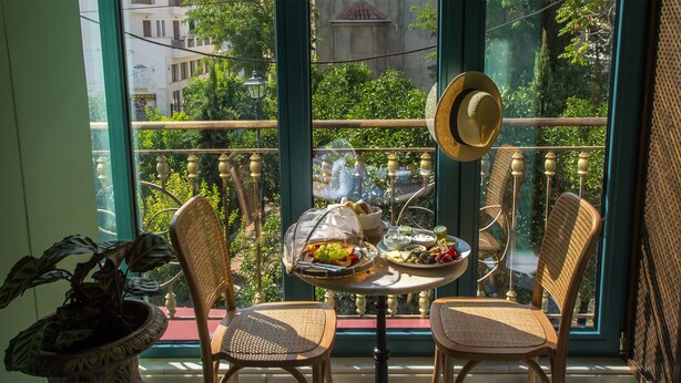 A balcony with wicker chairs, a table with food, and a hat on the railing. - Juan Rodriguez Hacienda (Athens)