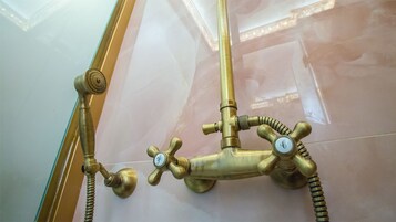 Messingistä valmistettu kylpyhuoneen hana, jossa on useita kahvoja ja joustava letku.