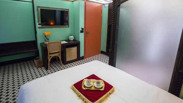 A hotel room with a bed, a desk, a chair, a small table, a mirror, and a door. - Juan Rodriguez Hacienda (Athens)