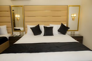 A hotel room with a large bed, two bedside tables, a nightstand, and a mirror. - Hotel White Season Gulberg (Lahore)