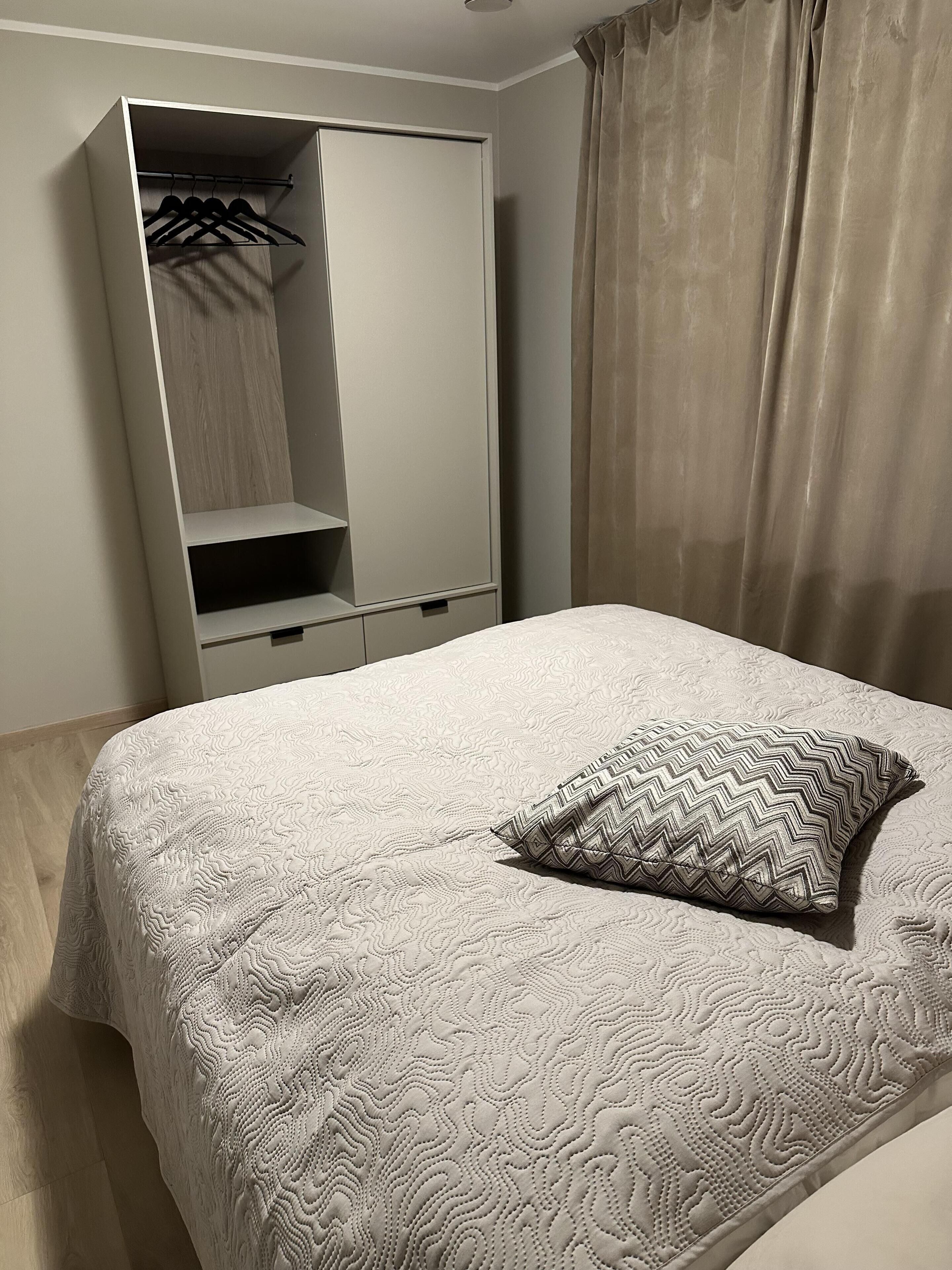 A bedroom with a bed, a wardrobe, and a hanging closet.