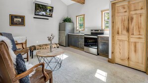 A modern kitchen with wooden beams, a dining area with a round table, and a large wooden door. - The Retreat @ Alpine South, Massive deck with view (Tryon)