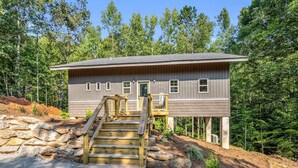 A two-story house with a wooden staircase leading to a front door, surrounded by a forest. - The Retreat @ Alpine South, Massive deck with view (Tryon)
