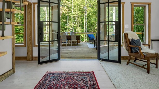A spacious room with a large arched doorway leading to an outdoor deck with a table and chairs. - The Retreat @ Alpine South, Massive deck with view (Tryon)