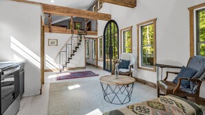 A spacious living area with a high ceiling, wooden beams, a staircase, and large windows offering views of the outdoors. - The Retreat @ Alpine South, Massive deck with view (Tryon)