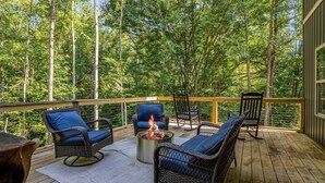 A wooden deck with wicker furniture and a fire pit, surrounded by trees. - The Retreat @ Alpine South, Massive deck with view (Tryon)