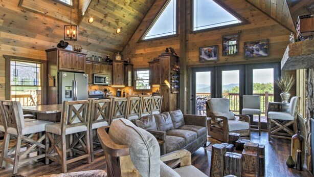 A rustic cabin interior with a dining area, seating, and a kitchen. - Newly Listed Cabin w/ Game Room, Hot Tub & Theater (Sevierville)