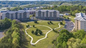 A multi-story hotel with a central courtyard, surrounded by lush greenery and hilly terrain.