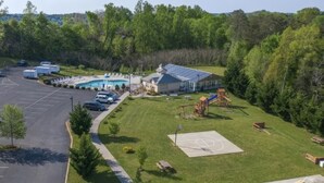 An aerial view of a campground with a swimming pool, RV parking, a playground, and a basketball court.