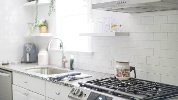 A modern kitchen with white cabinetry, a stainless steel sink, and a gas stove. - Lovely Historic District Retreat (Columbus)