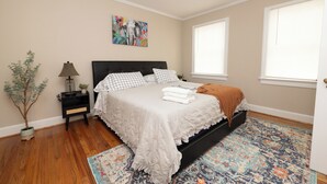 A bedroom with a bed, nightstand, lamp, and a decorative plant. - Lovely Historic District Retreat (Columbus)