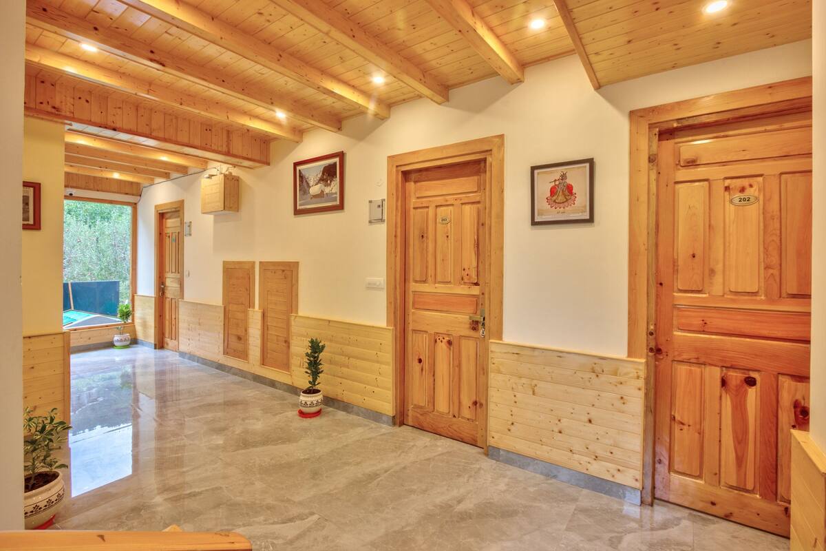 Un couloir avec des portes en bois, un sol carrel é et des plantes en pot.
