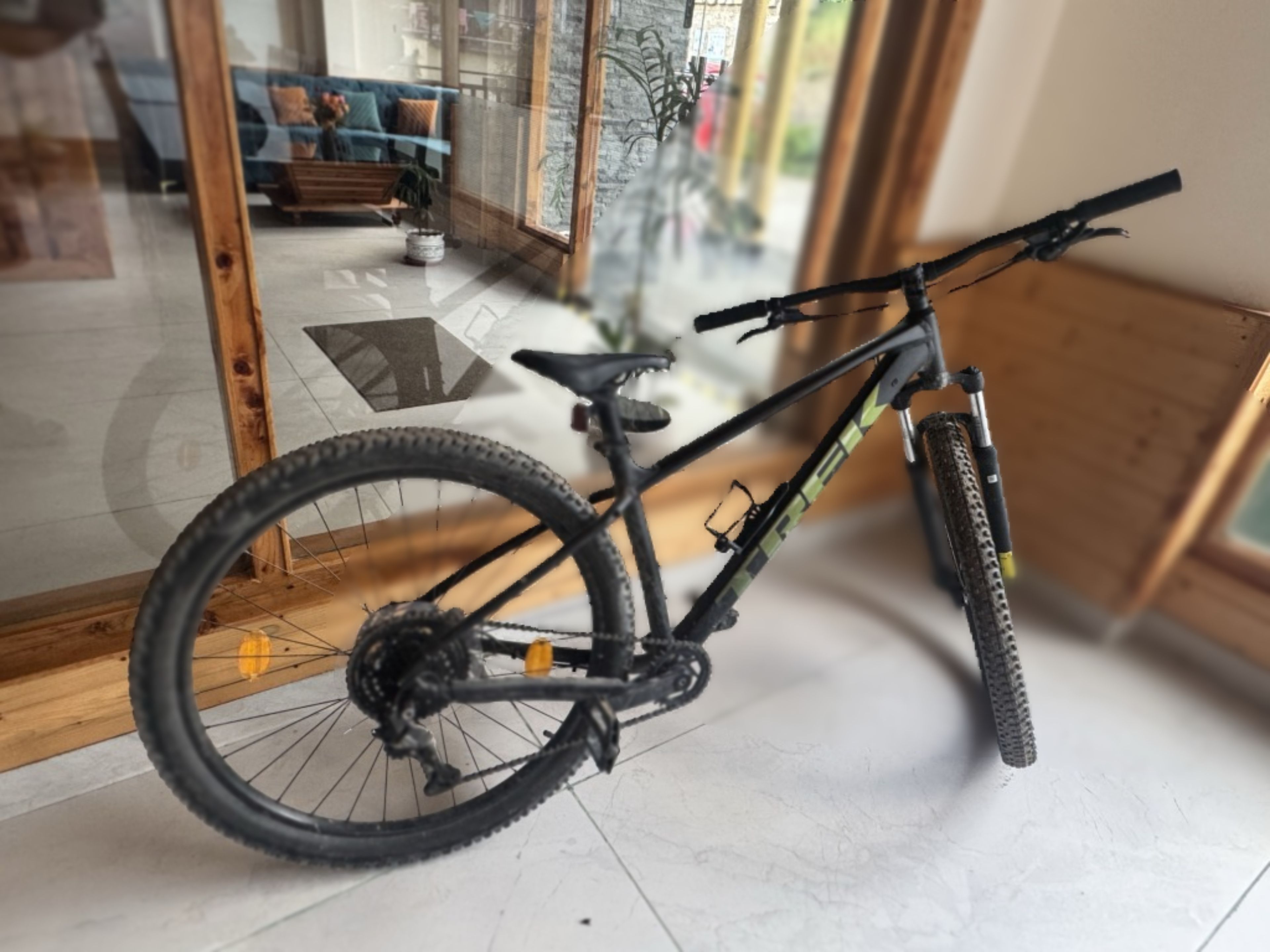 A bicycle indoors with a view of a living room through a glass door.