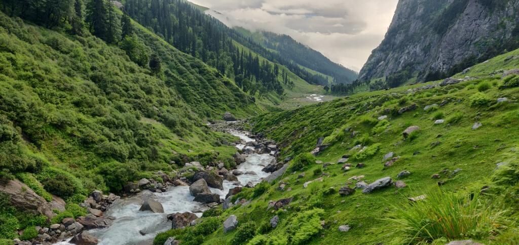 Une rivière qui traverse une vallée, bordée de collines verdoyantes et d’un paysage rocheux.