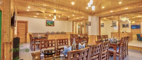 A wooden interior with a dining area, wooden ceiling, and a television mounted on the wall.