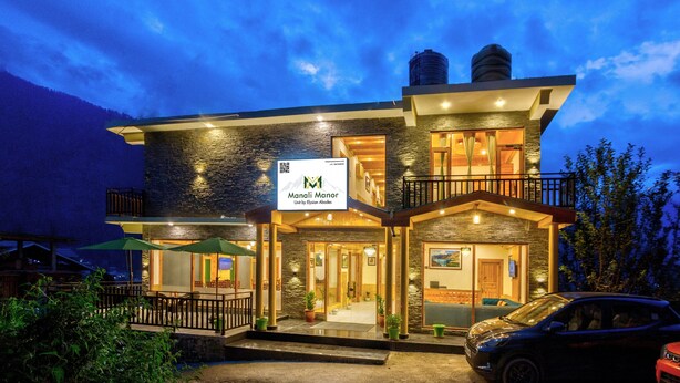 A two-story hotel with a stone facade, a balcony, and a sign indicating it is a hotel. - Manali Manor (Manali)