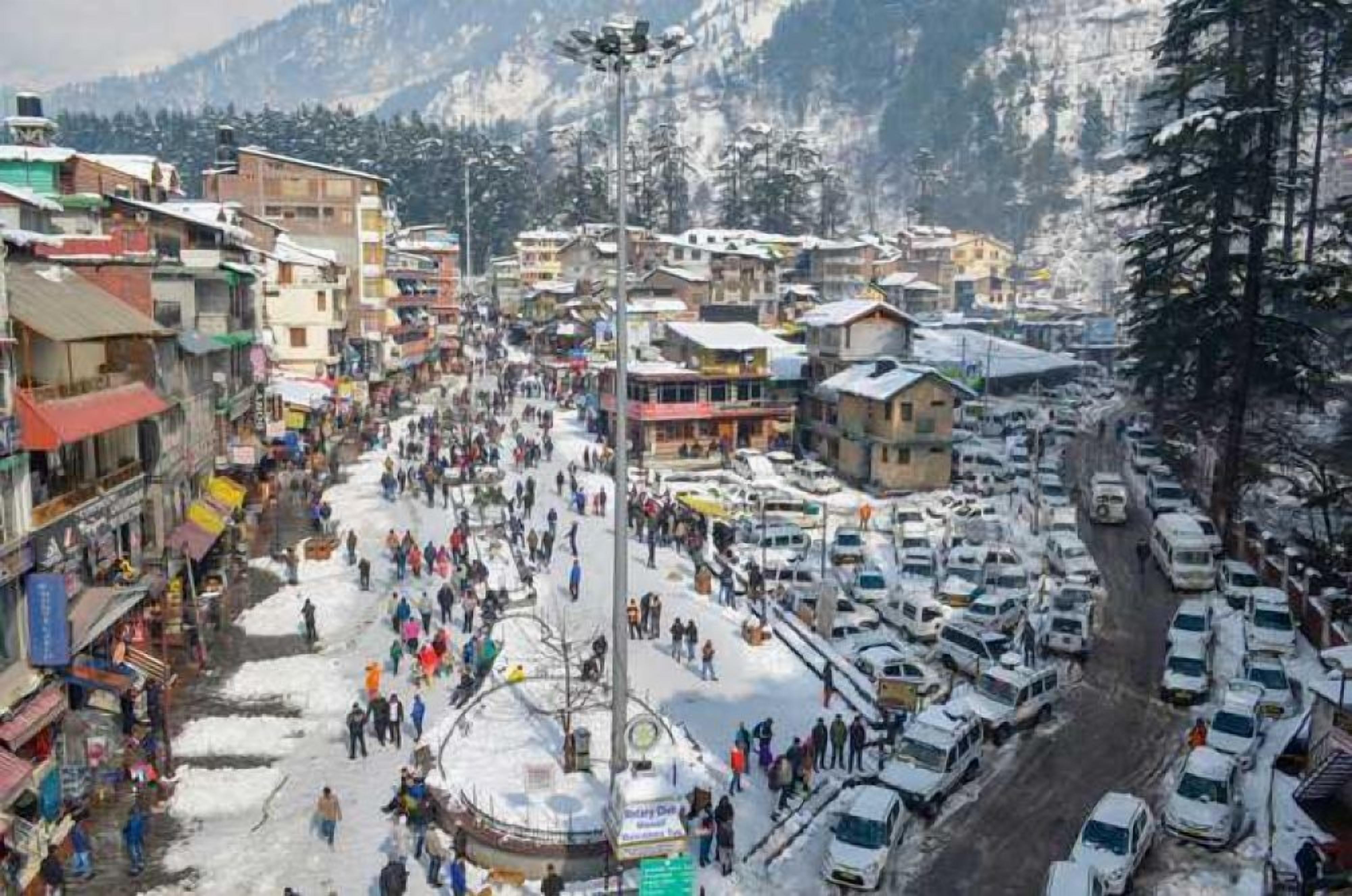 A busy street scene in a mountainous area with buildings and parked cars.