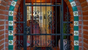 A brick entrance with a metal gate and decorative tiles.