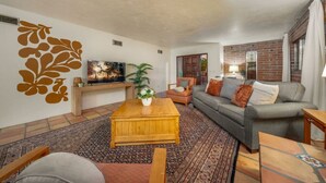 A living room with a wooden coffee table, a grey sofa, and a TV on a stand.
