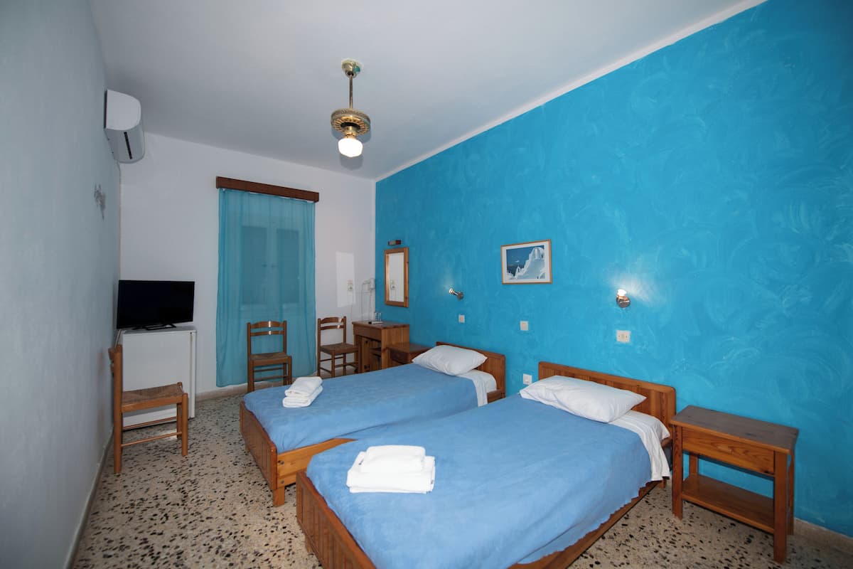 A room with two beds, a desk, a chair, a television, and a mirror.