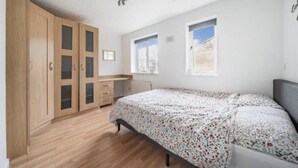 Ein Schlafzimmer mit einem Bett, einem Holzschrank und zwei Fenstern.