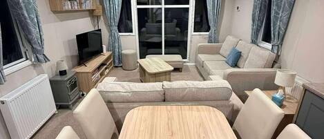 Una sala de estar con un sofá, televisor, mesa de centro y mesa de comedor.