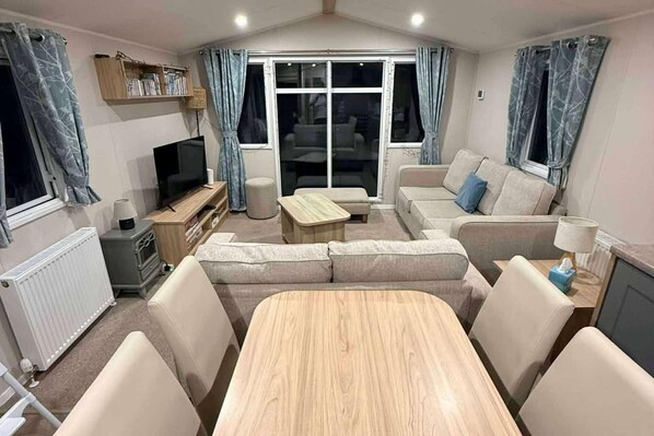 Una sala de estar con un sofá, televisor, mesa de centro y mesa de comedor.
