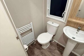 Un baño pequeño con inodoro, radiador y lavamanos.