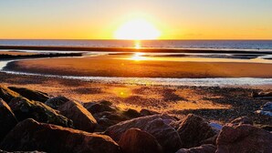 A beach with a sunset, rocky foreground, and calm sea. - Caravan-blackpool-familyfriendly-activities (Fleetwood)