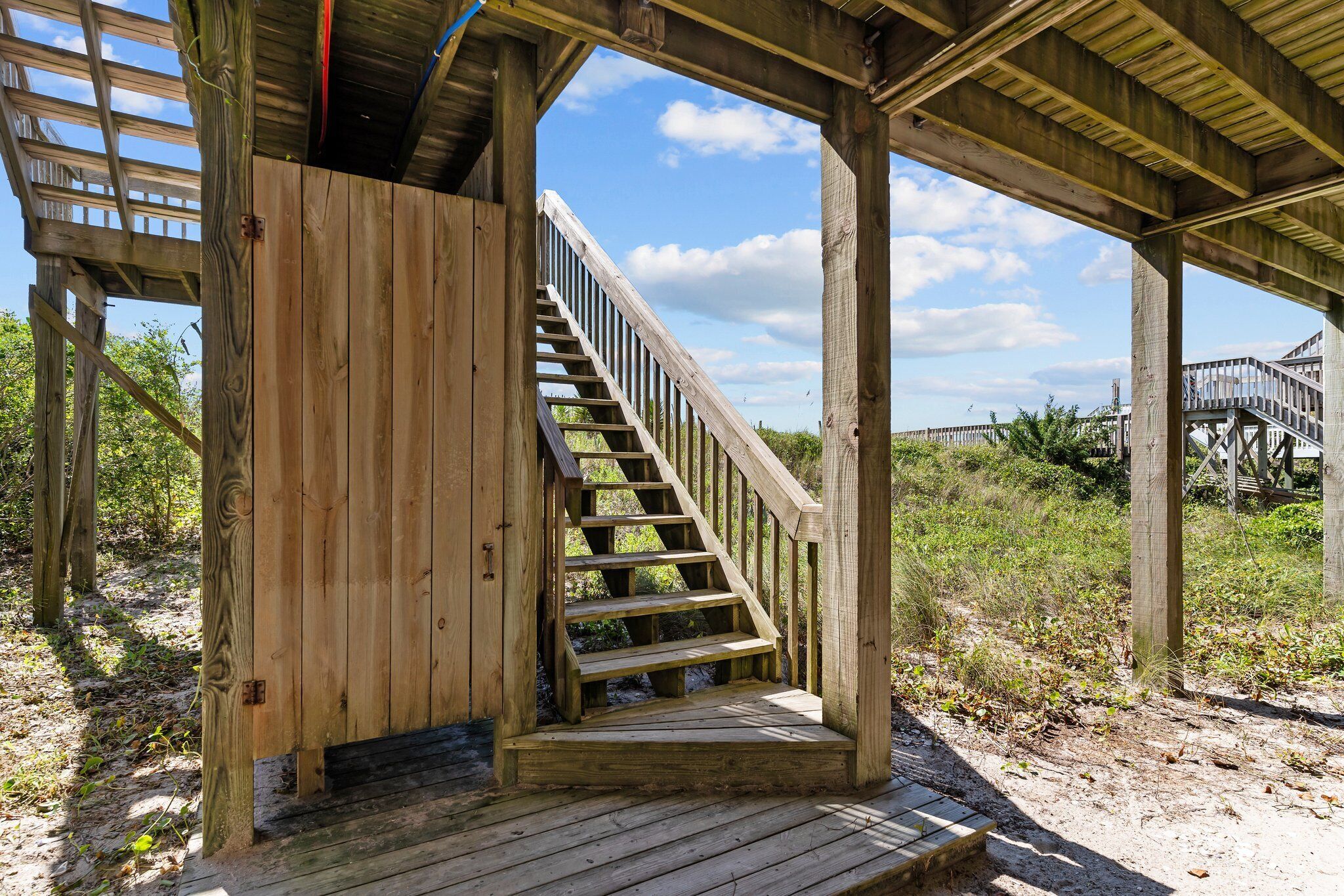 Un escalier en bois mène à une zone abritée d’où l’on peut admirer le ciel et la végétation environnante.