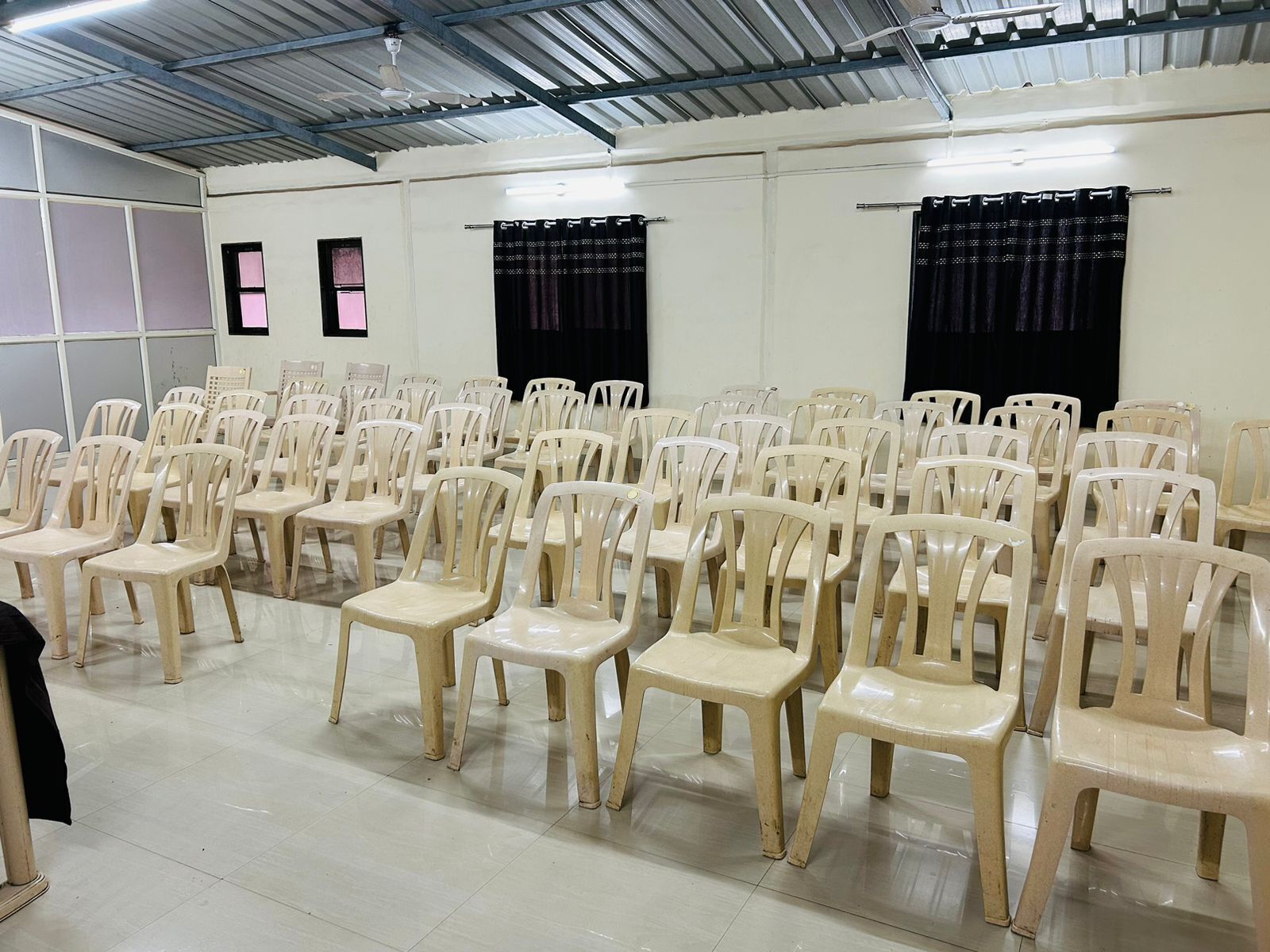 Um salão com fileiras de cadeiras de plástico bege dispostas para acomodação.
