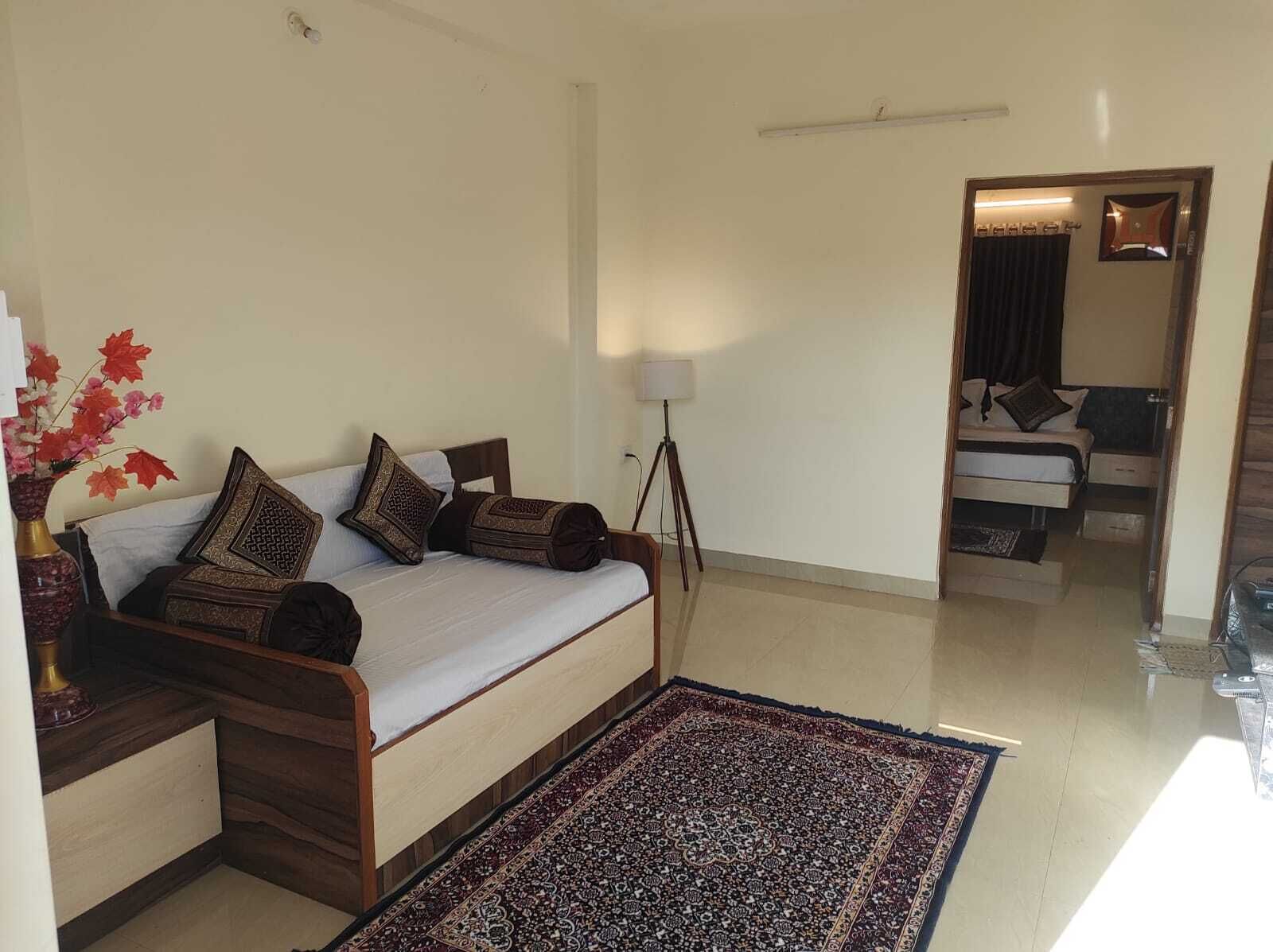 A bedroom with a bed, a floor lamp, a rug, and a vase with flowers.