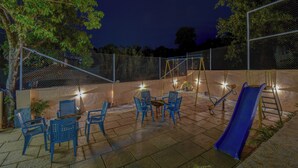 An outdoor patio with blue chairs and a slide, surrounded by a fence and trees. - Hotel Padmavati Palace Mahabaleshwar (Mahabaleshwar)