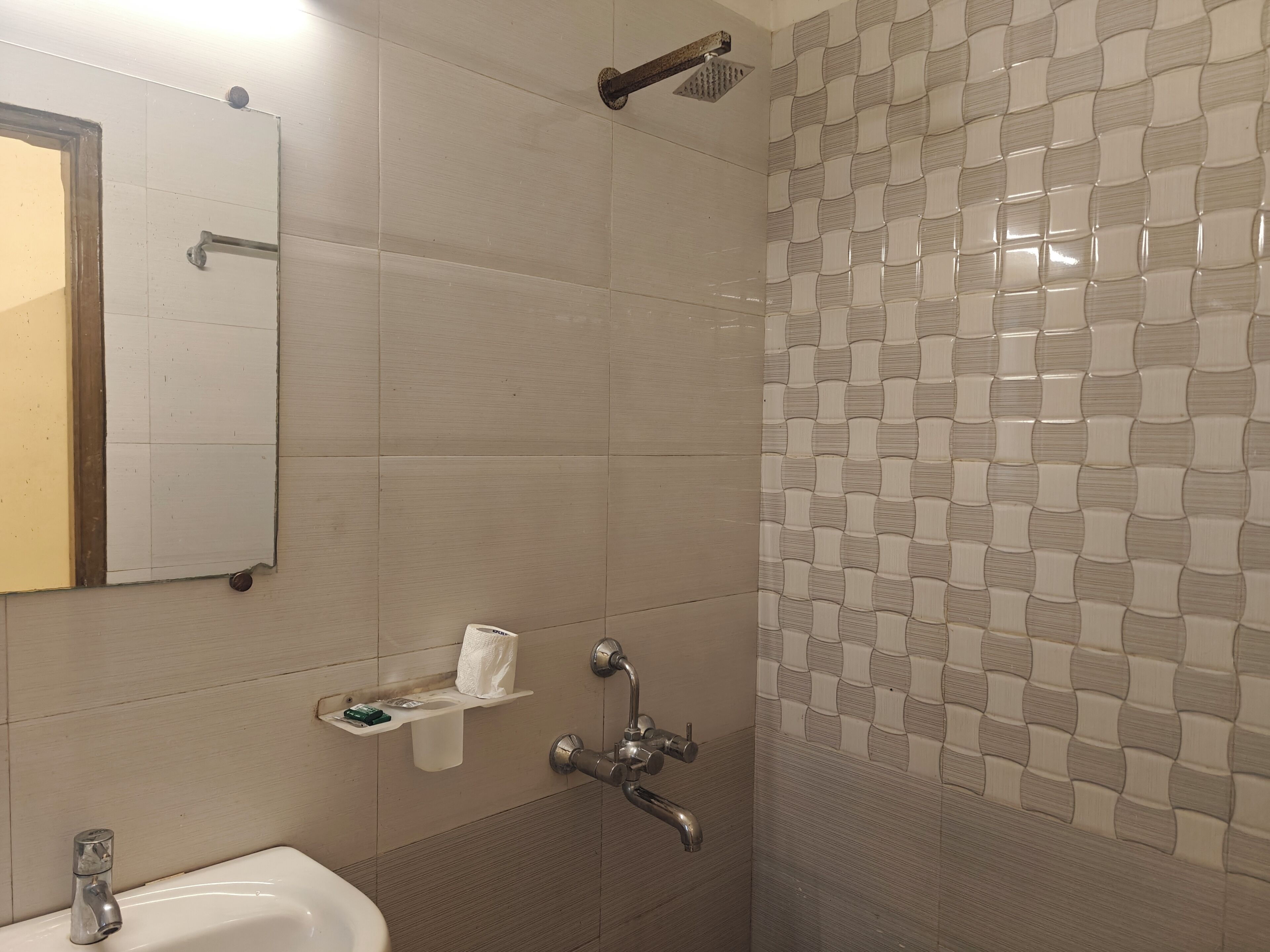 A bathroom with a sink, mirror, towel rack, shower, and patterned tiles.