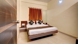 A bedroom with a bed, wooden headboard, curtains, and a ceiling fan. - Hotel Padmavati Palace Mahabaleshwar (Mahabaleshwar)