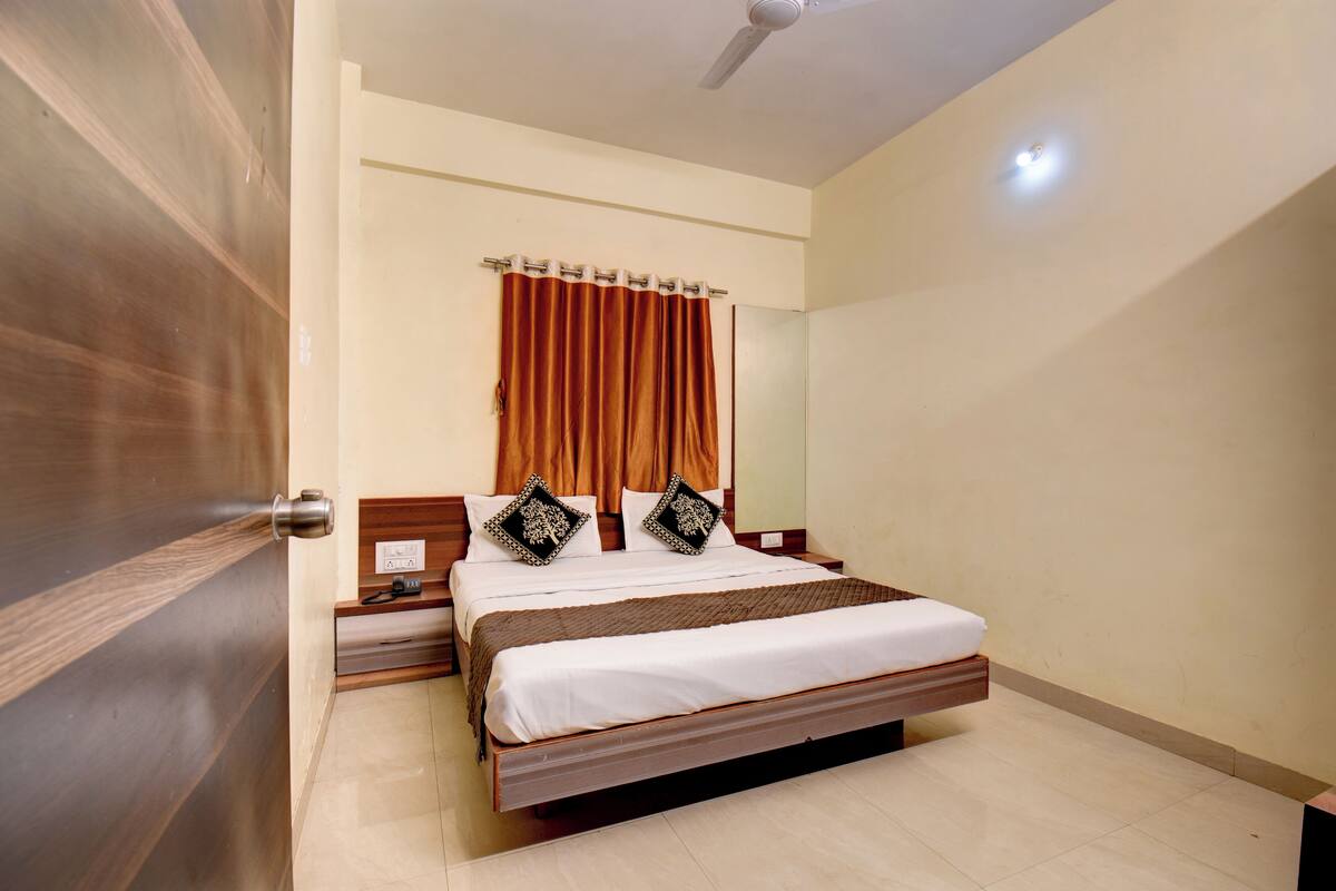 Une chambre à coucher avec un lit, une tête de lit en bois, des rideaux et un ventilateur de plafond.