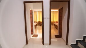 Un pasillo de hotel con una puerta doble que da a una habitación con una cama y una mesita.