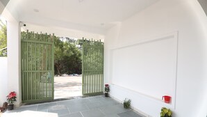 Un vestíbulo espacioso con un portón verde, plantas en macetas y suelo de baldosas.