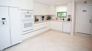 A modern kitchen with white cabinetry, a built-in oven, a coffee maker, and a blender. - Beachfront Bliss: Ground Floor Condo at The Islands Club, 7 Mile Beach, #05 (Grand Cayman)