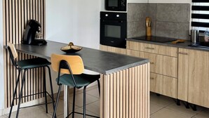 Una cocina moderna con una isla central, armarios de madera y un microondas.